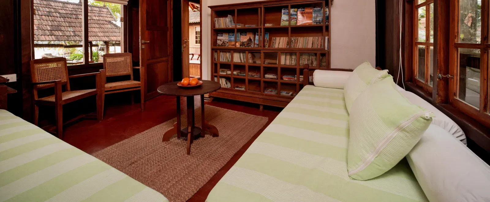 A view of the living room with comfortable seating and a book shelf at Heritage Cottage at Samiira on Ashtamudi Lake.