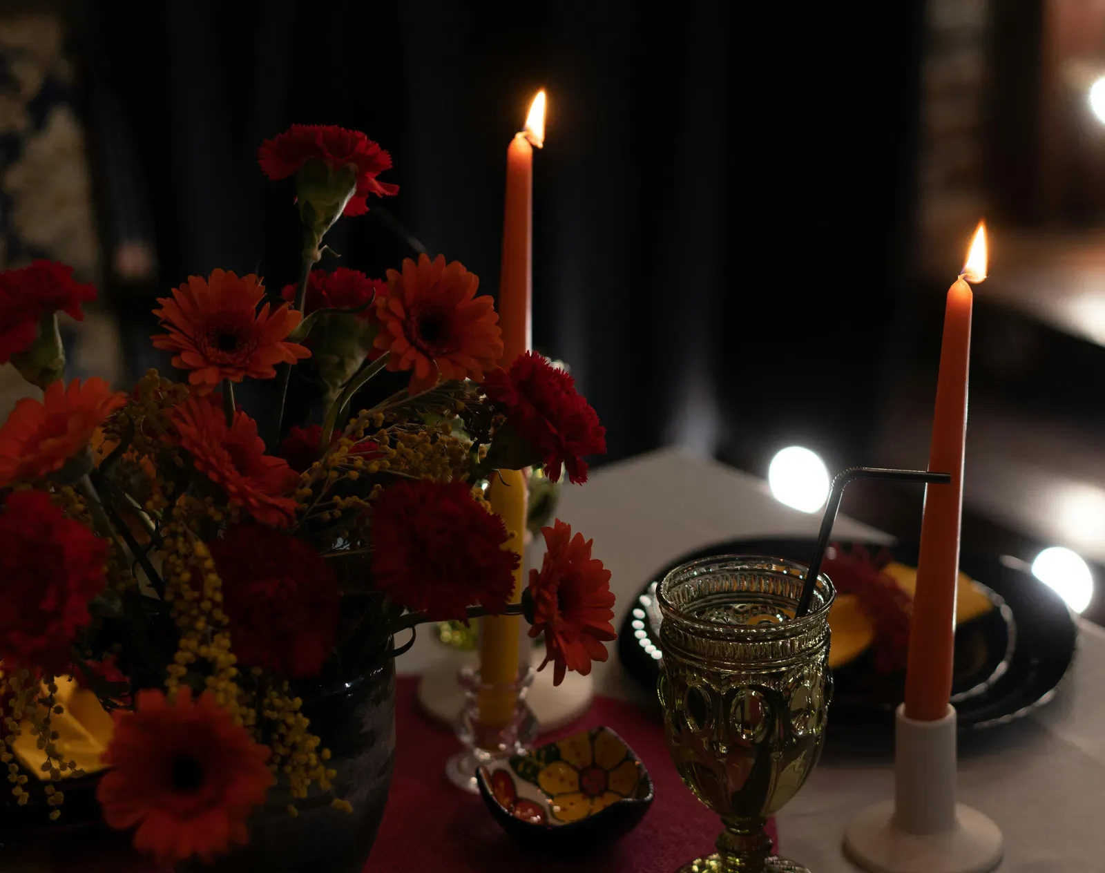 Photo of candles placed next to flowers on a table.