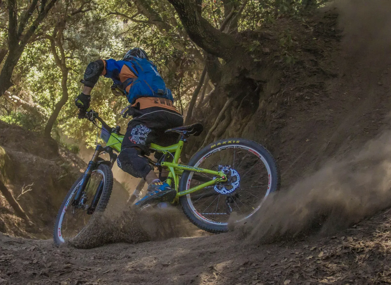 A man cycling on an off road surrounded by a forest.